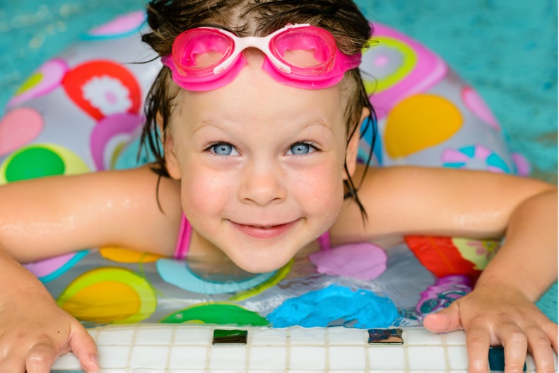 Child in a swimming pool with pink goggles
