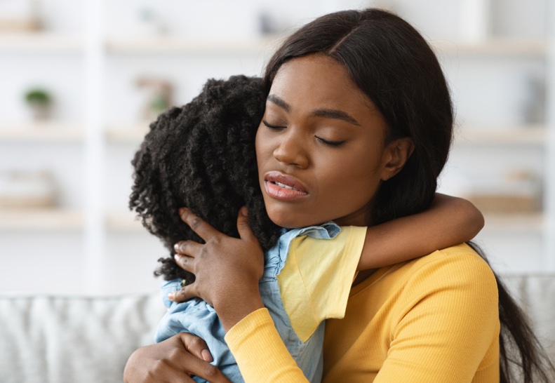 caring African-American woman hugging a child